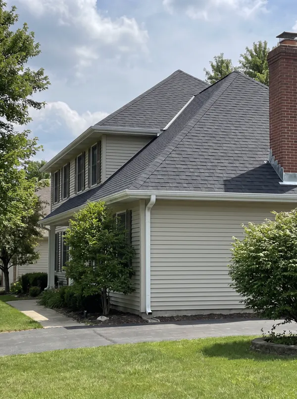 A new charcoal shingle roof with straight courses and white gutters